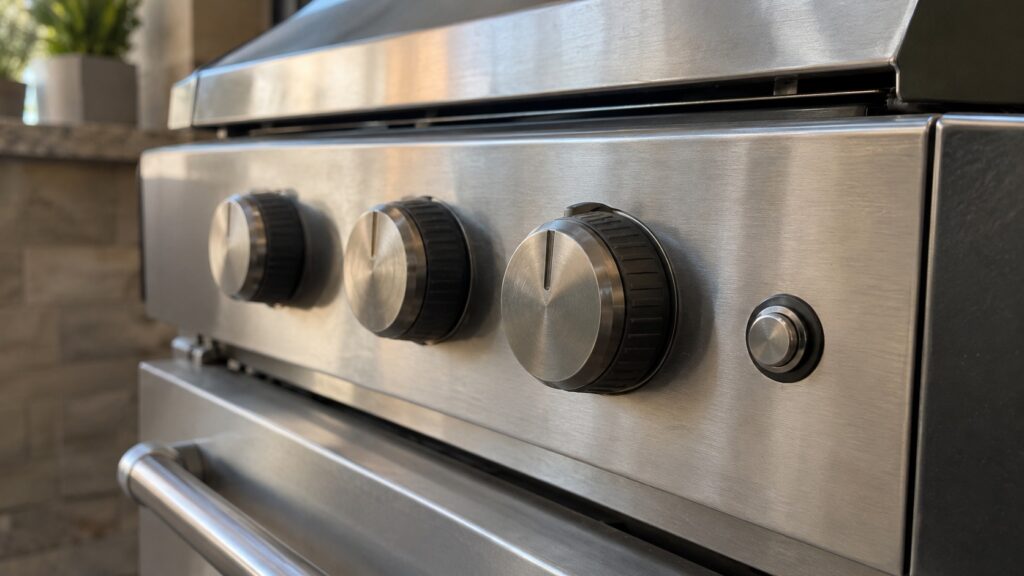 A close view of grill control knobs and the small ignition button beside them, no text, letters or symbols